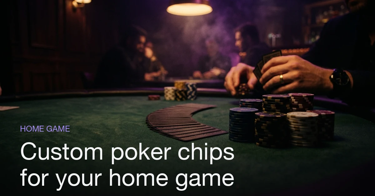 Stacks of custom poker chips on green felt at a home poker game, with cards fanned out under warm light.